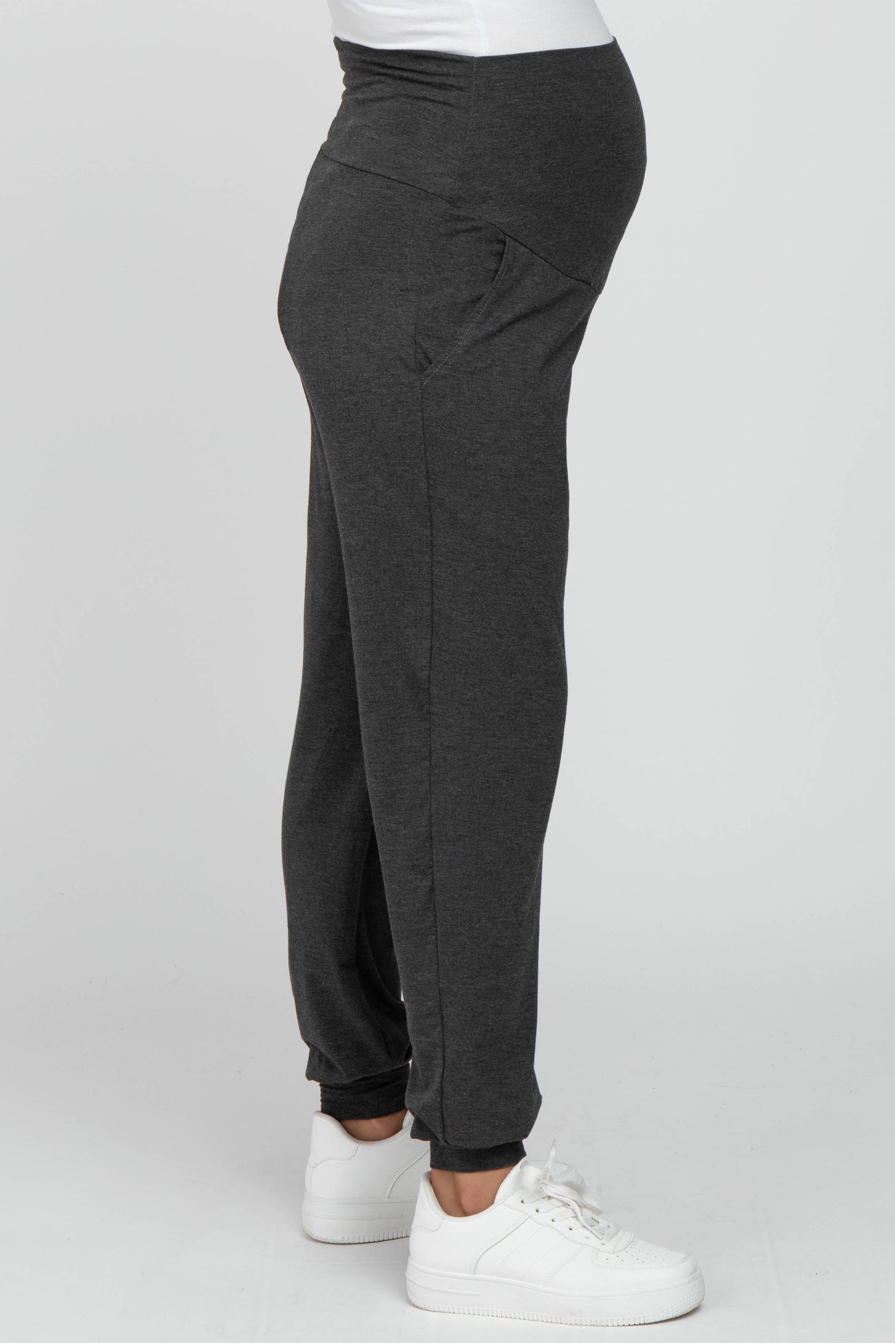 woman wearing gray maternity joggers with a waistband designed for a baby bump