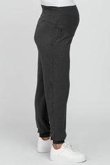 woman wearing gray maternity joggers with a waistband designed for a baby bump