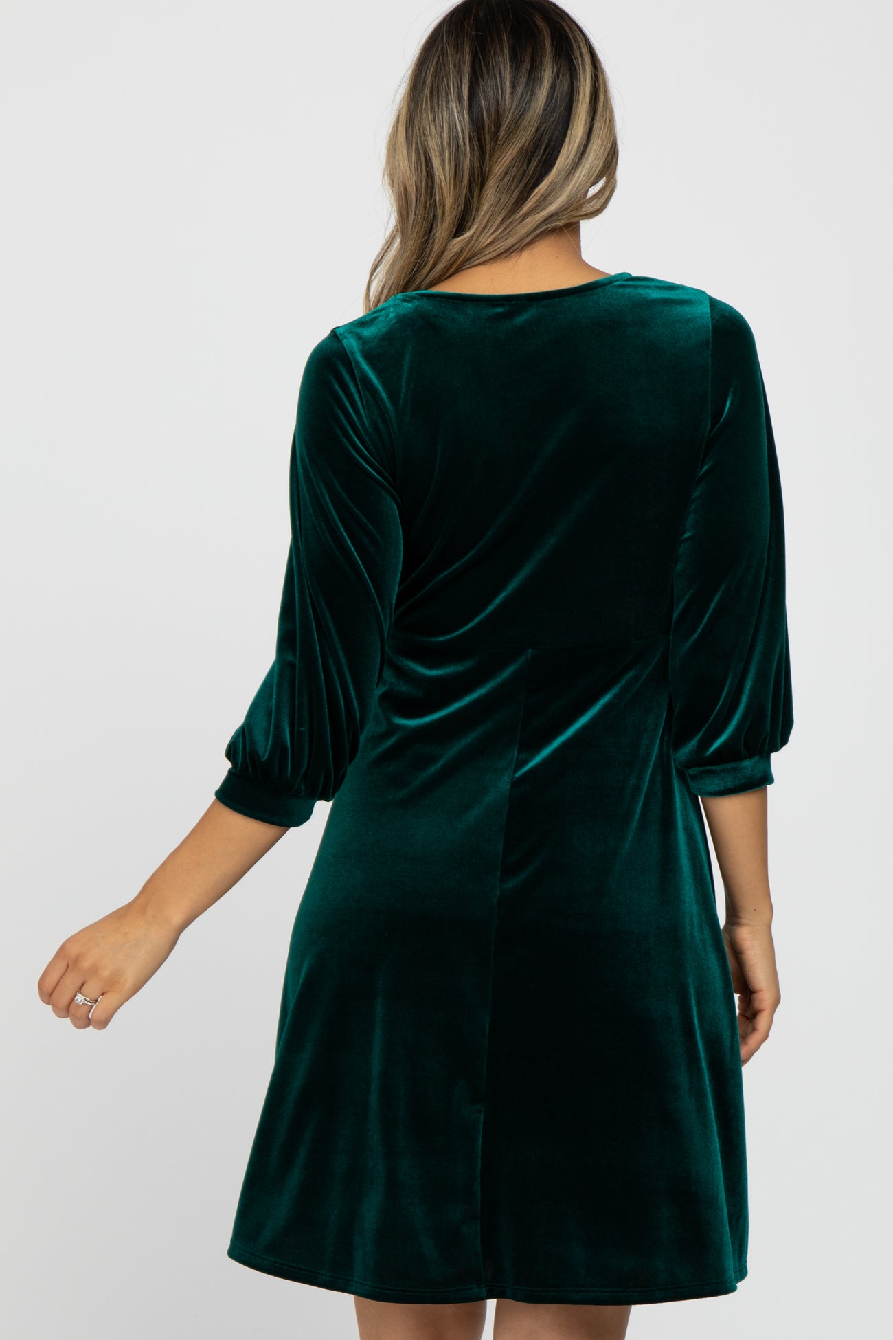 woman wearing a green velvet dress with three-quarter length sleeves and a flared skirt, viewed from the back