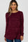 woman wearing a burgundy marled long sleeve top with a crossover front design and relaxed fit, paired with blue jeans