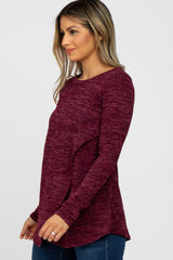 woman wearing a long sleeve burgundy marled nursing top with a crossover front panel and blue jeans