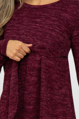 woman wearing a maroon long sleeve top with a gathered waist and a subtle scoop neckline