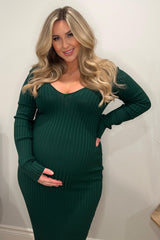 woman wearing a dark green long sleeve maternity dress with ribbed texture, holding her baby bump
