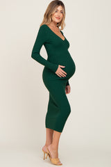 woman wearing a green ribbed maternity dress with a v-neck and long sleeves, showcasing her baby bump