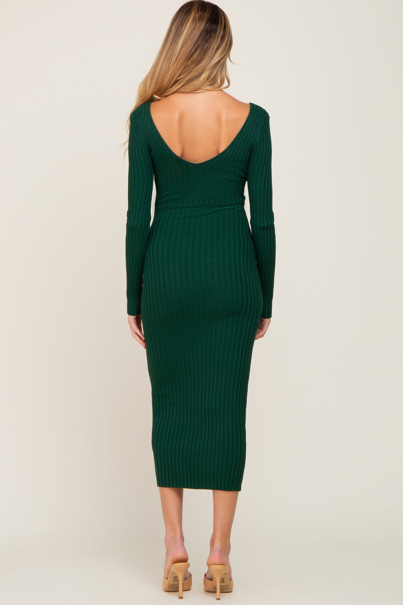 woman wearing a dark green ribbed maternity dress with a deep v-back and long sleeves