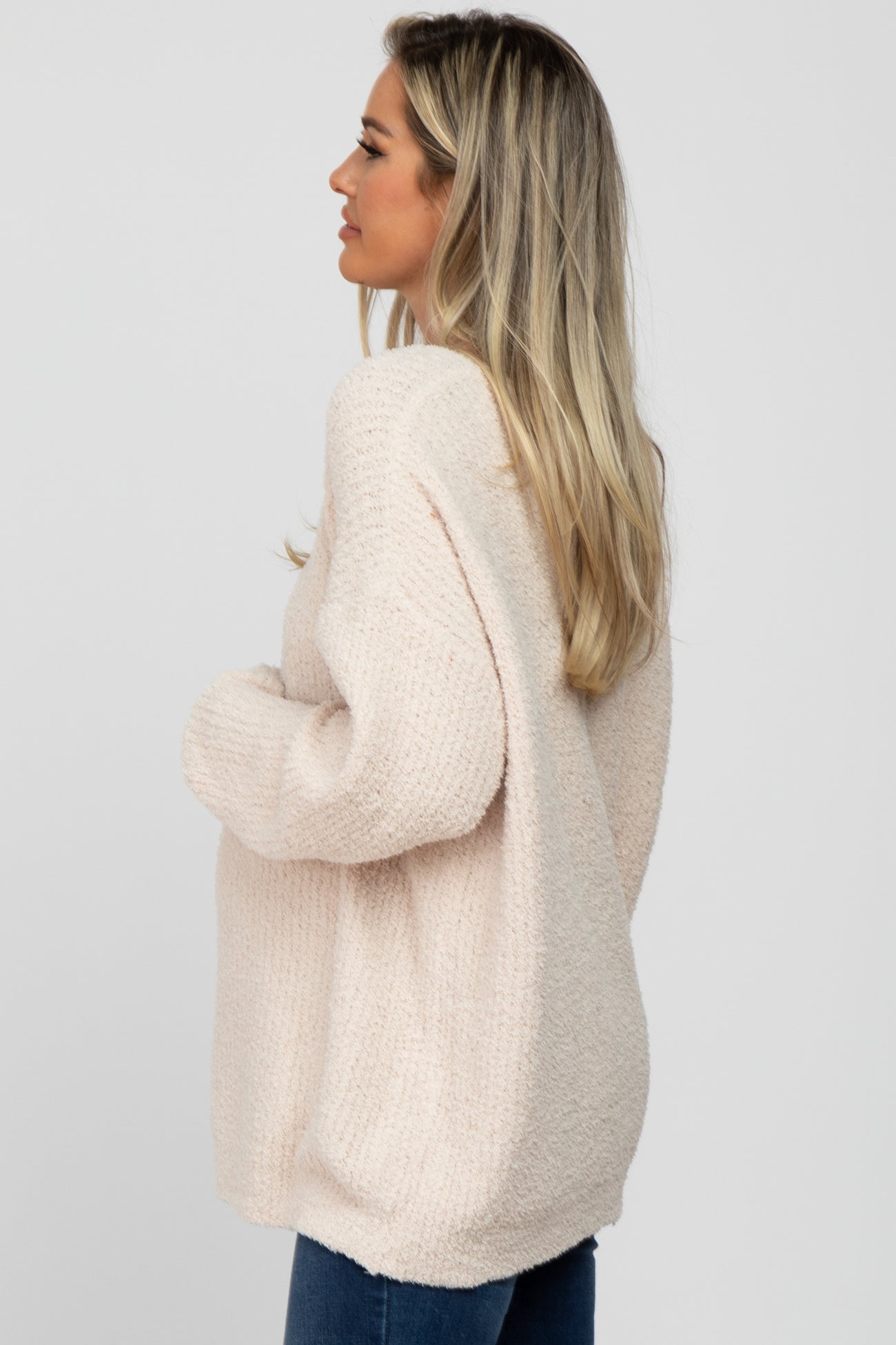 woman wearing a cozy light pink oversized maternity sweater with a relaxed fit and long sleeves