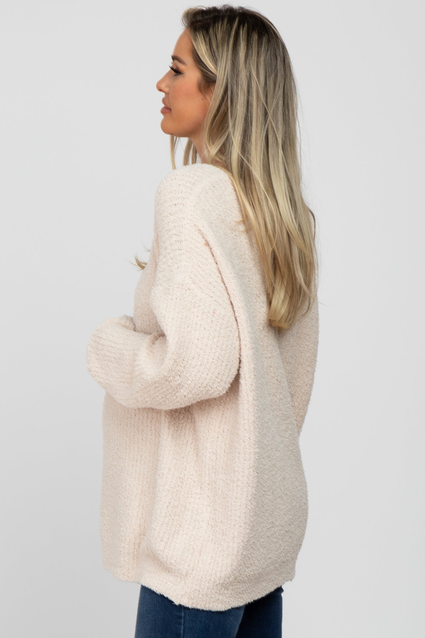 woman wearing a cozy light pink oversized maternity sweater with a relaxed fit and long sleeves