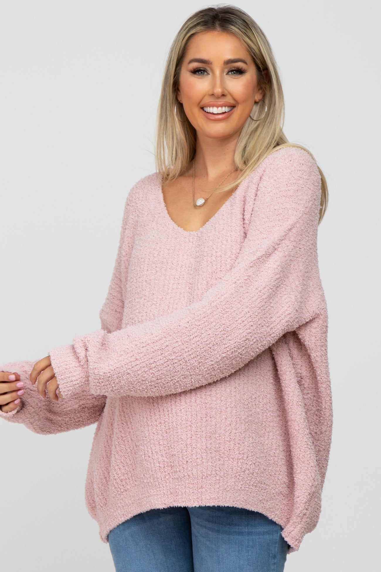 woman wearing a soft pink oversized maternity sweater with a v-neck and long sleeves