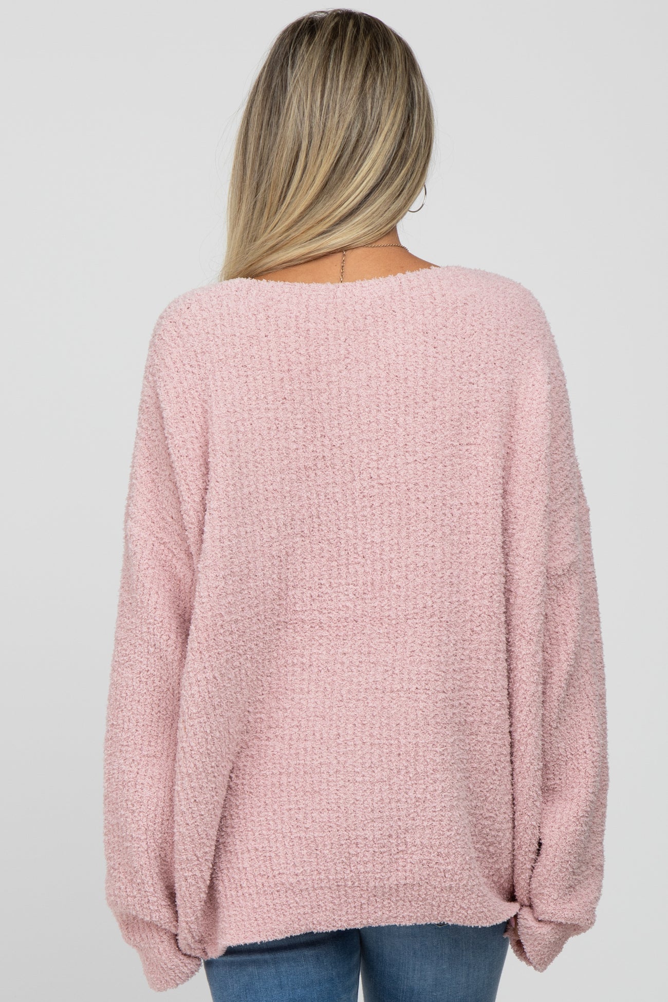 woman wearing a soft pink oversized maternity sweater, shown from the back with a relaxed fit and wide sleeves