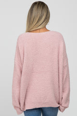 woman wearing a soft pink oversized maternity sweater, shown from the back with a relaxed fit and wide sleeves