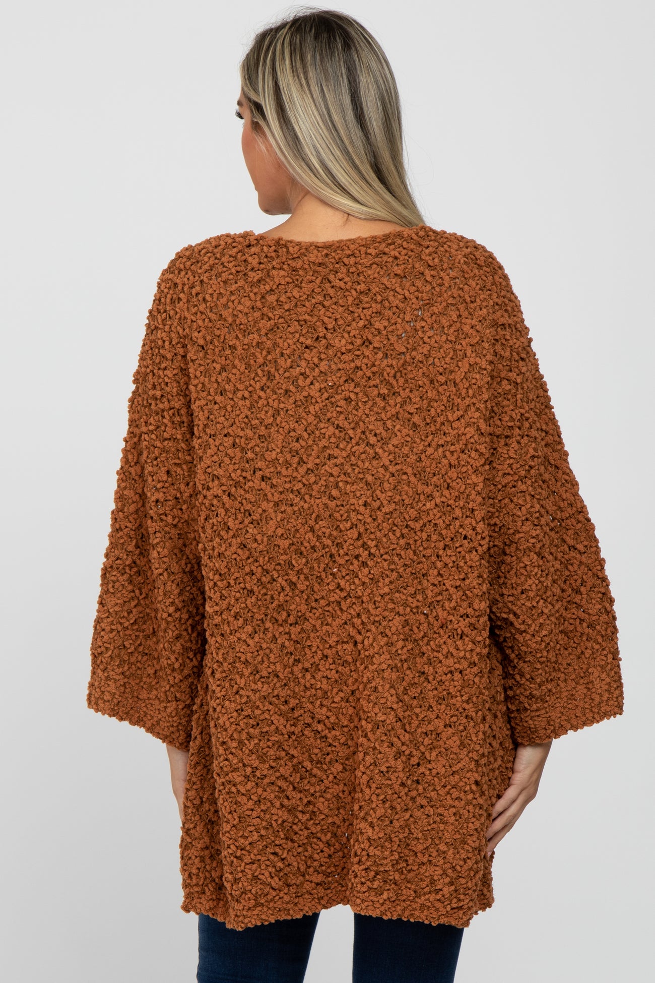woman wearing an oversized rust-colored fuzzy maternity sweater with three-quarter sleeves and a relaxed fit