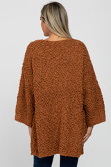 woman wearing an oversized rust-colored fuzzy maternity sweater with three-quarter sleeves and a relaxed fit