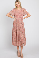 woman wearing a pink floral midi dress with short sleeves and pleated skirt, standing and smiling