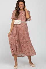 woman wearing a pink floral pleated midi dress with a white belt bag and cream pointed toe flats