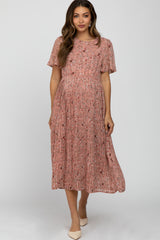 woman wearing a pink floral pleated maternity dress with short sleeves and a flowing silhouette