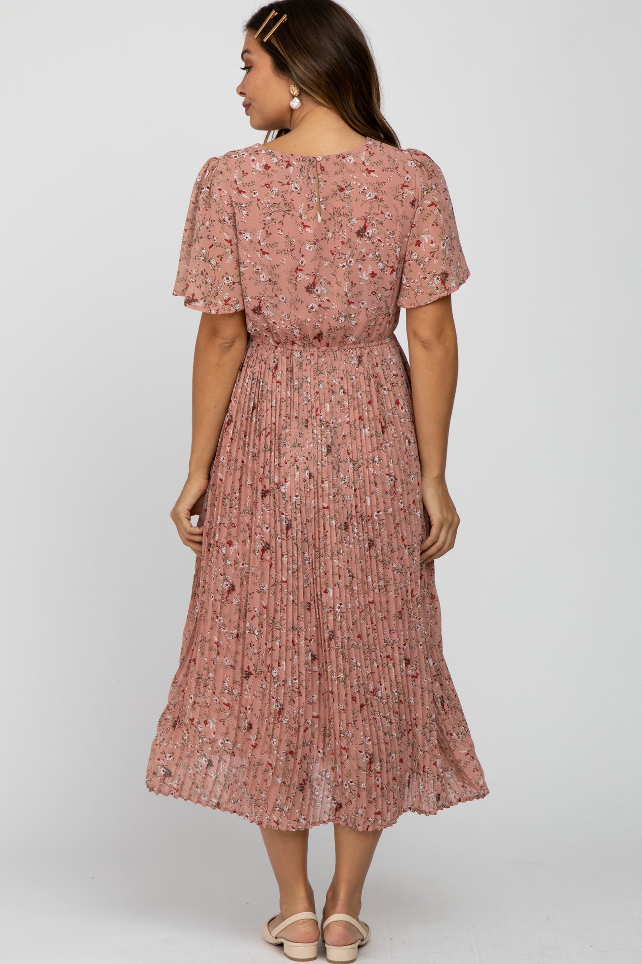 woman wearing a pink floral maternity dress with pleated skirt, showing the back view