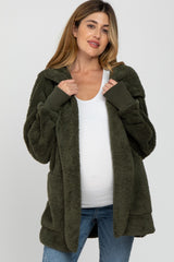 woman wearing olive green sherpa maternity cardigan over white top and blue jeans