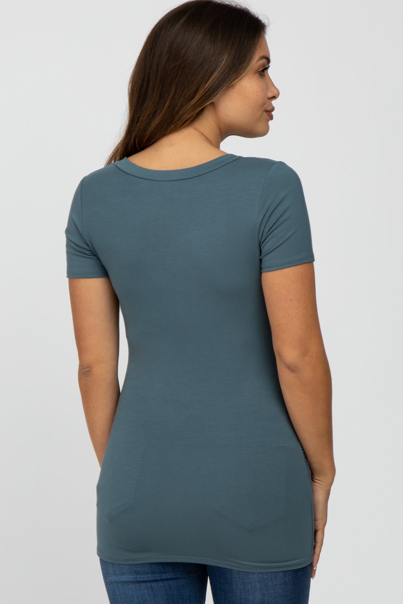 woman wearing a teal short sleeve maternity top, showing a fitted style from the back