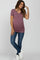 woman wearing a mauve short sleeve maternity top and showing her baby bump, paired with skinny jeans and white sneakers