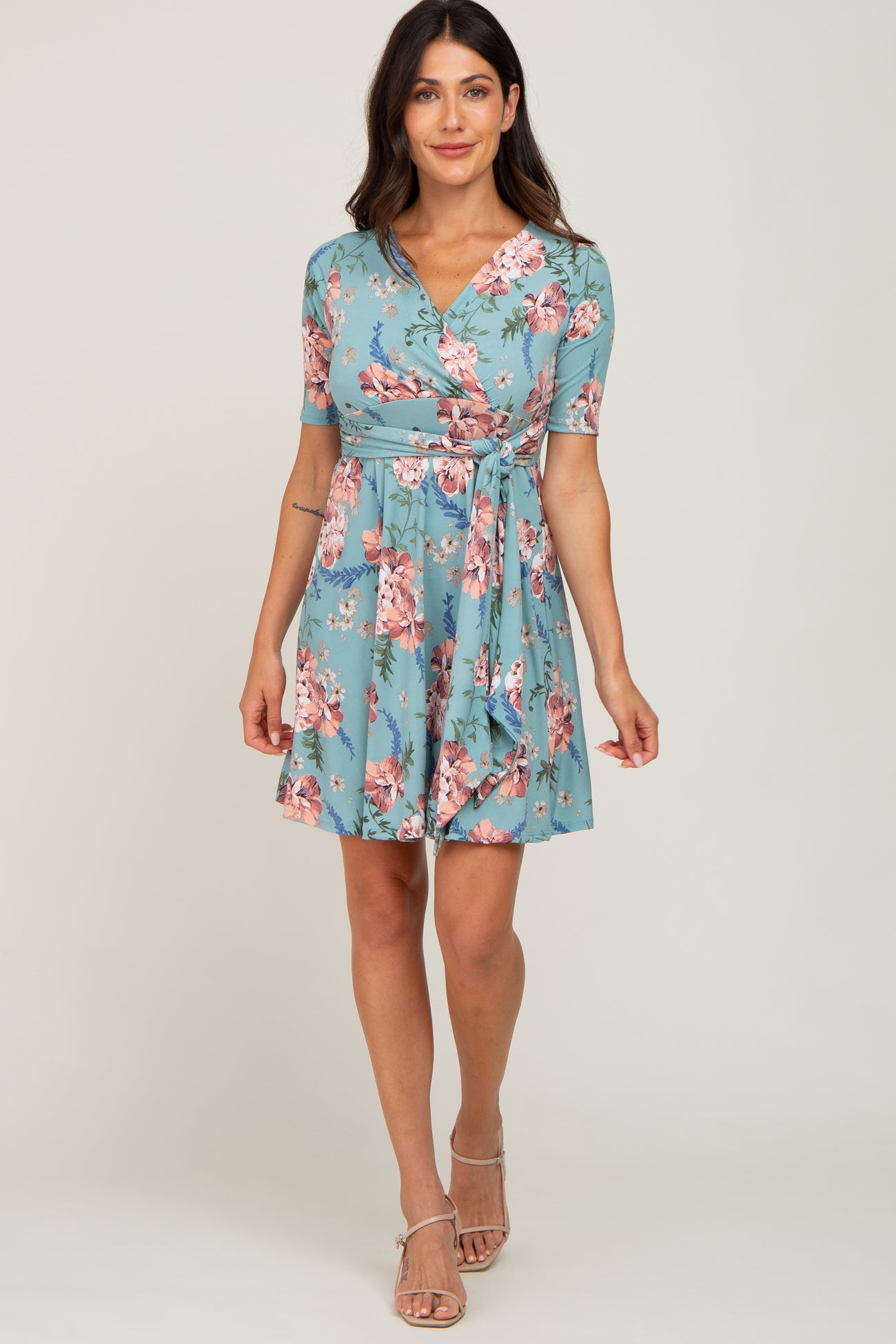 woman wearing a turquoise floral wrap dress with short sleeves and a tie waist