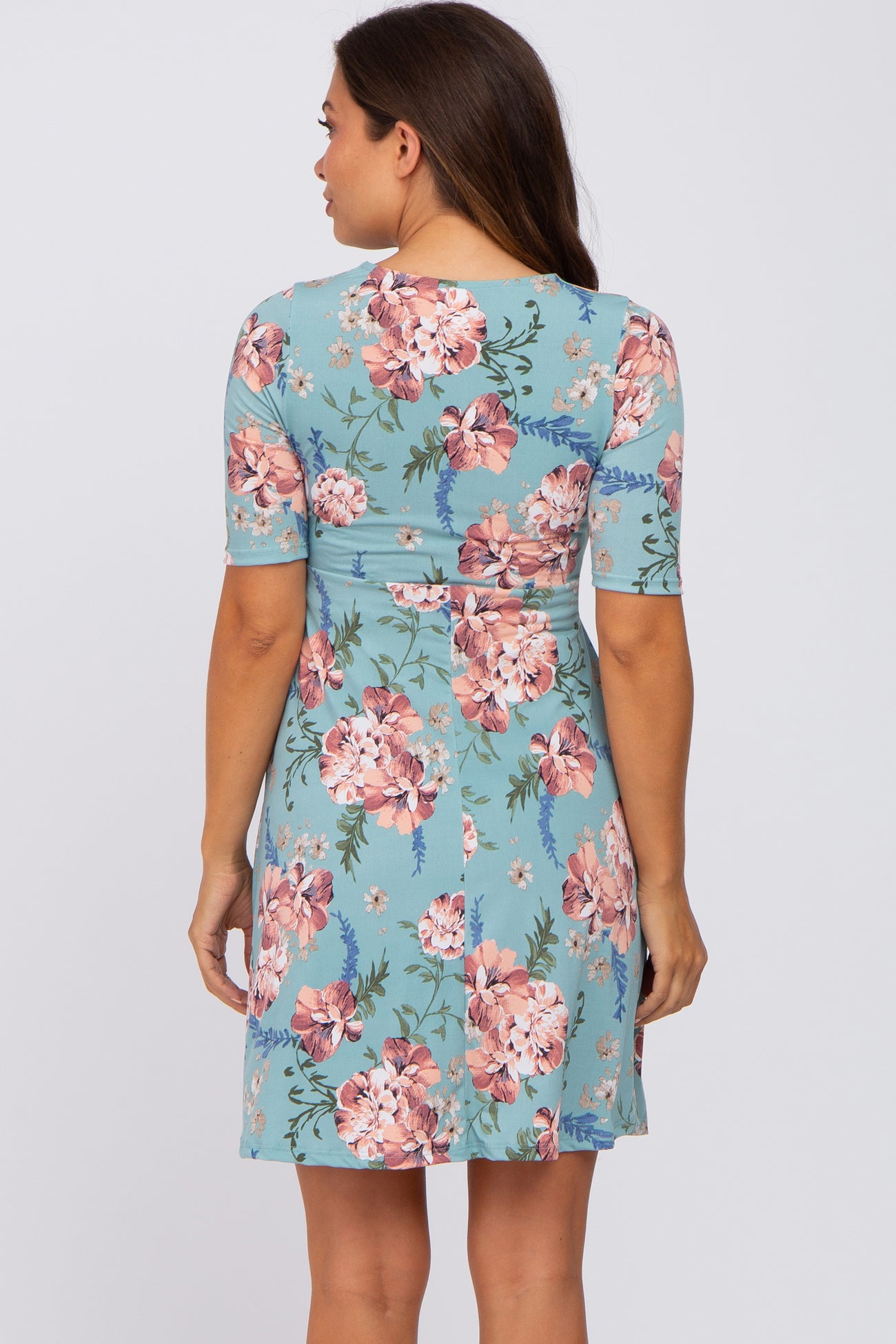 Back view of a woman wearing a light blue short sleeve maternity dress with a pink floral print pattern