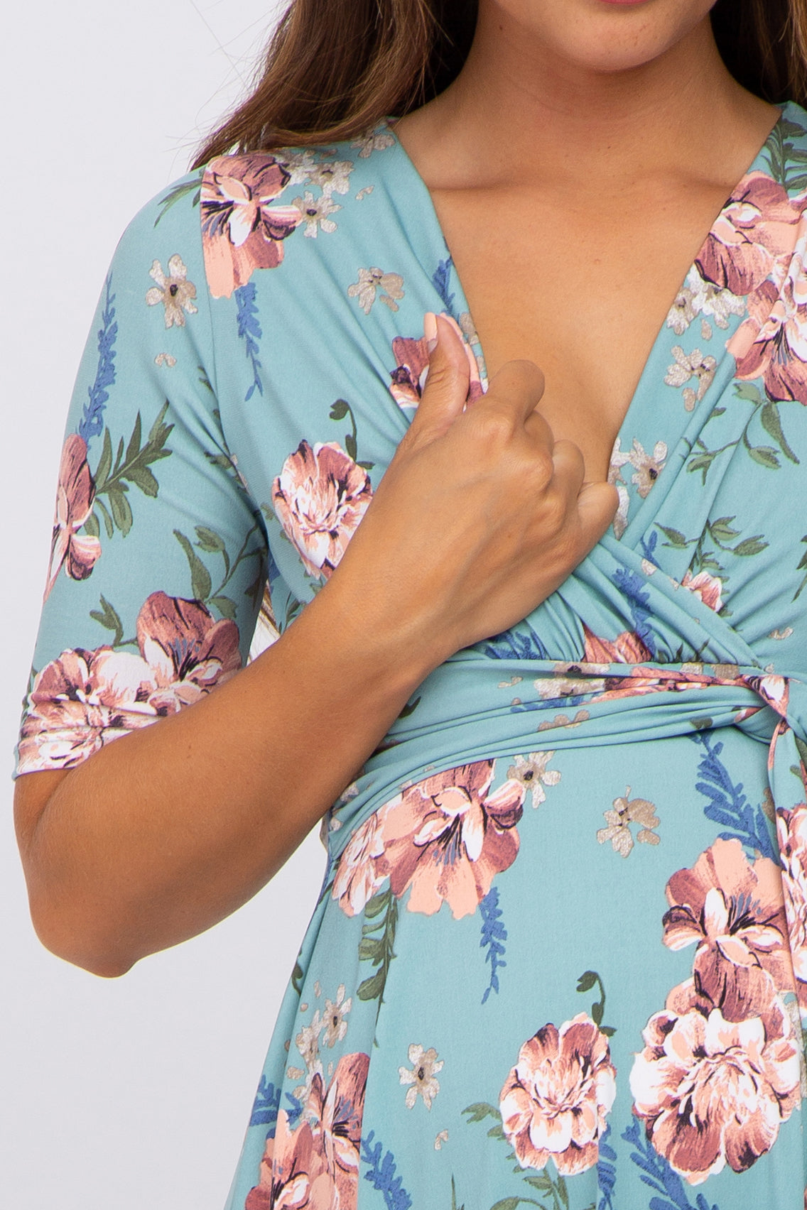 woman wearing a floral mint green maternity dress with a v-neck and short sleeves, revealing a baby bump