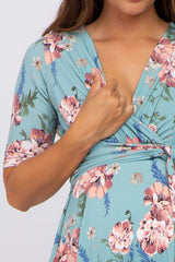 woman wearing a floral mint green maternity dress with a v-neck and short sleeves, revealing a baby bump