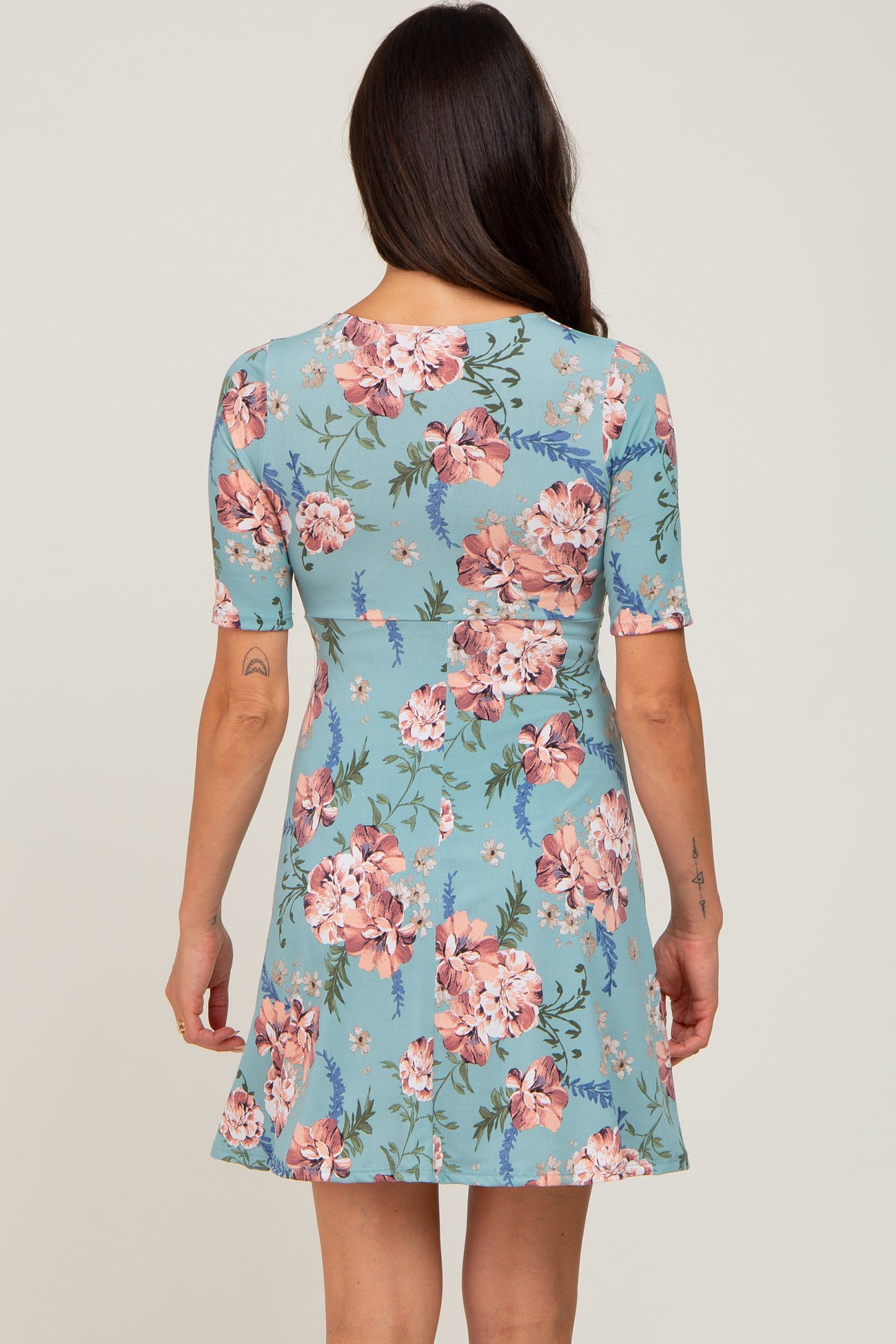 woman wearing a light blue floral short sleeve dress, showing the back view with a flared skirt