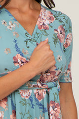 woman wearing a teal floral wrap dress with short sleeves and a tied detail at the waist