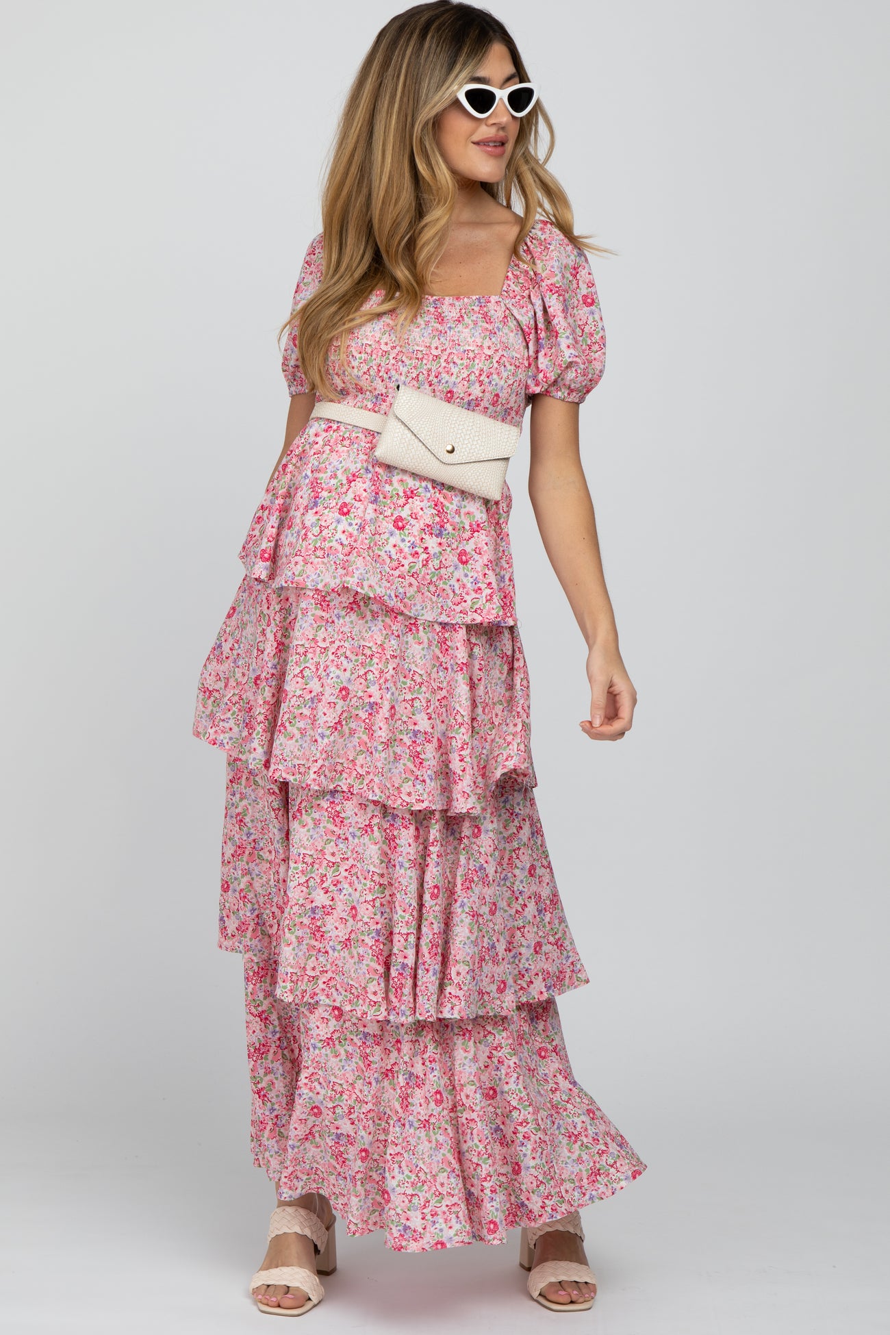 woman wearing a pink floral maternity dress with tiered ruffles and puff sleeves, showcasing her baby bump