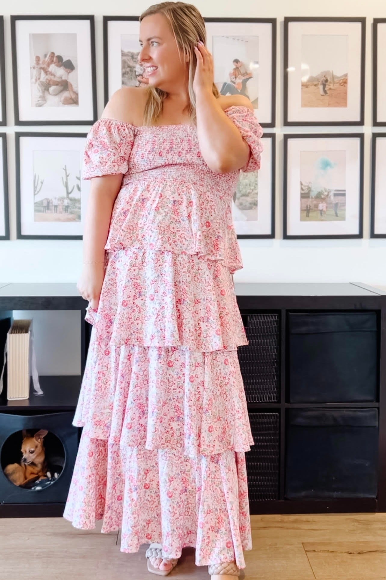woman wearing a pink floral off-the-shoulder maternity dress with tiered ruffles and a baby bump visible