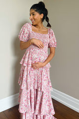 woman wearing a floral maternity dress with puff sleeves and tiered ruffles, holding her baby bump