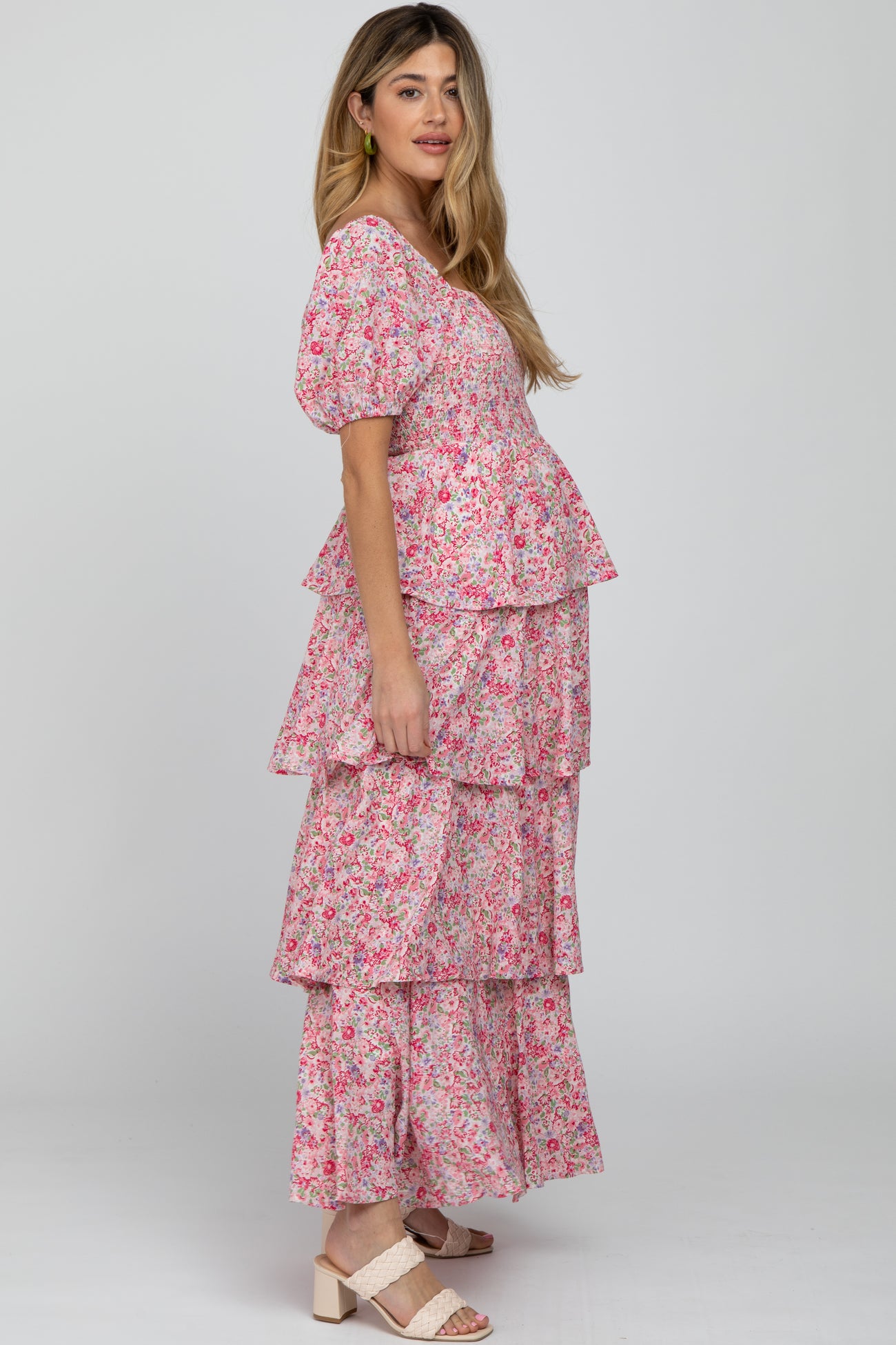 woman wearing a pink floral maternity maxi dress with tiered layers and a visible baby bump