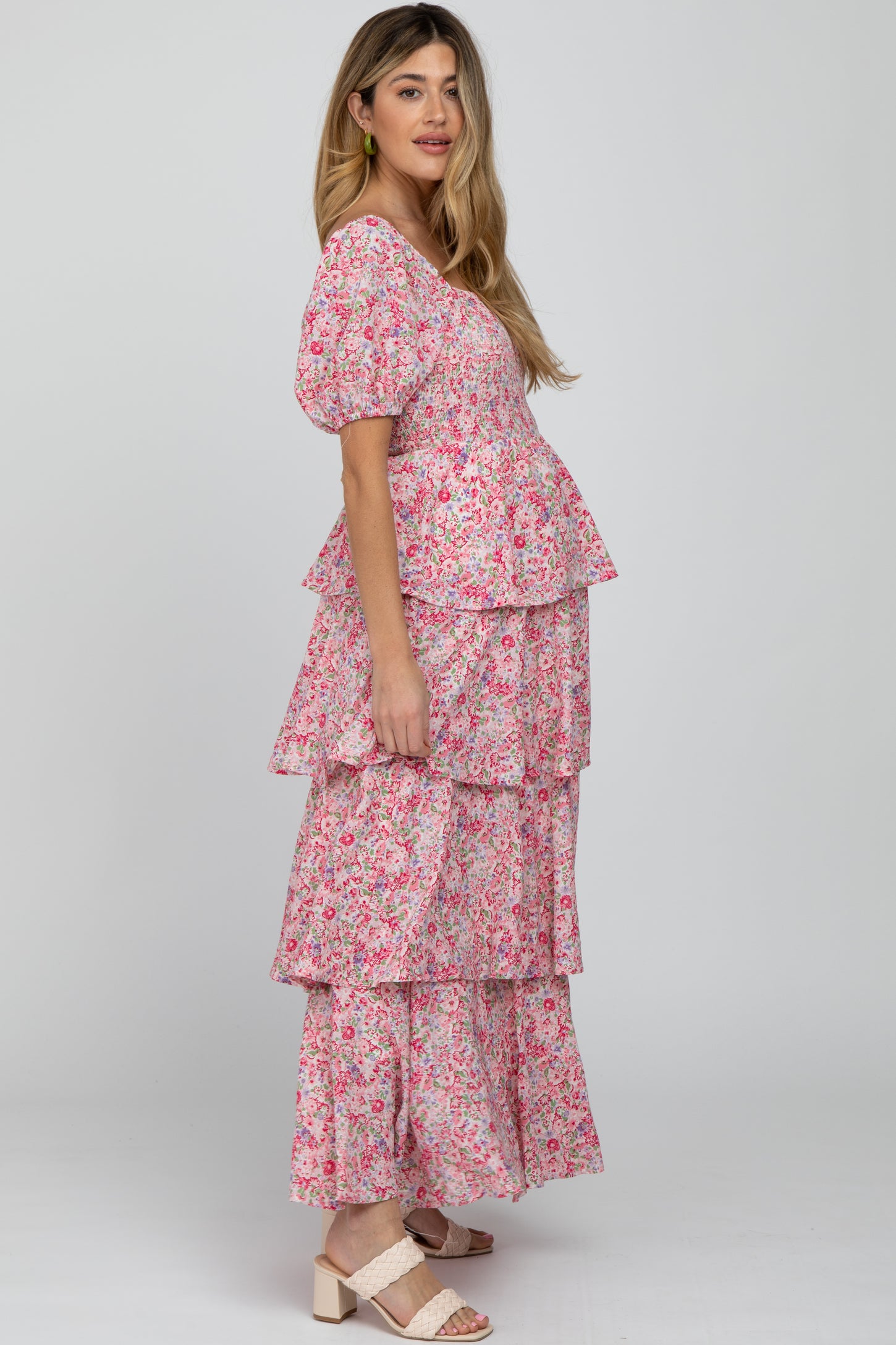 woman wearing a pink floral maternity maxi dress with tiered layers and a visible baby bump