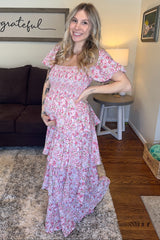woman wearing a pink floral maternity dress with ruffle sleeves and a visible baby bump