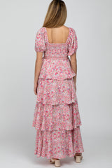 woman wearing a pink floral maternity maxi dress with puff sleeves and tiered ruffles, seen from the back