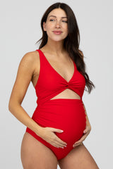 woman wearing a red maternity swimsuit with a twist front detail and showing her baby bump