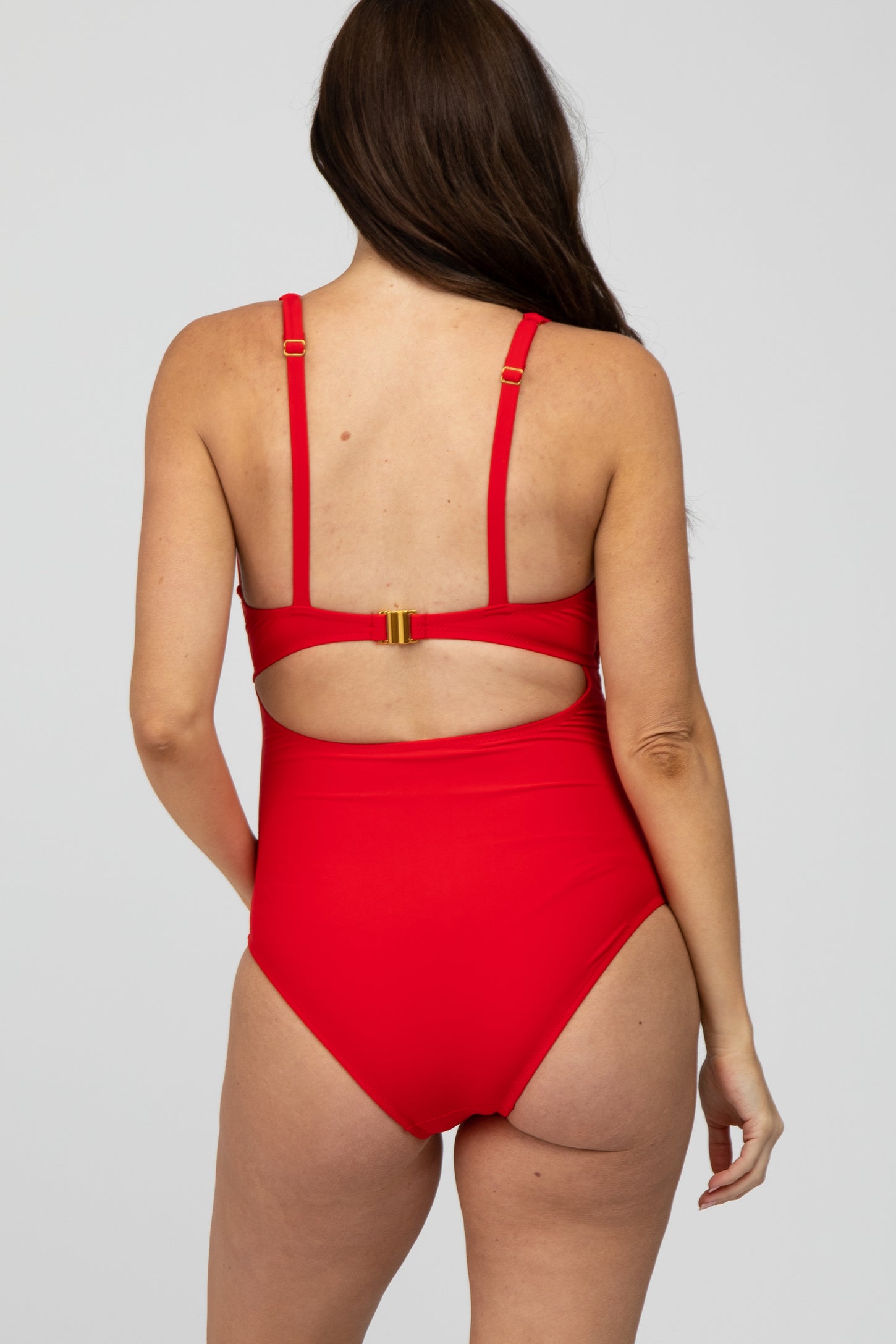 woman wearing a red maternity swimsuit with adjustable straps and a stylish back cutout
