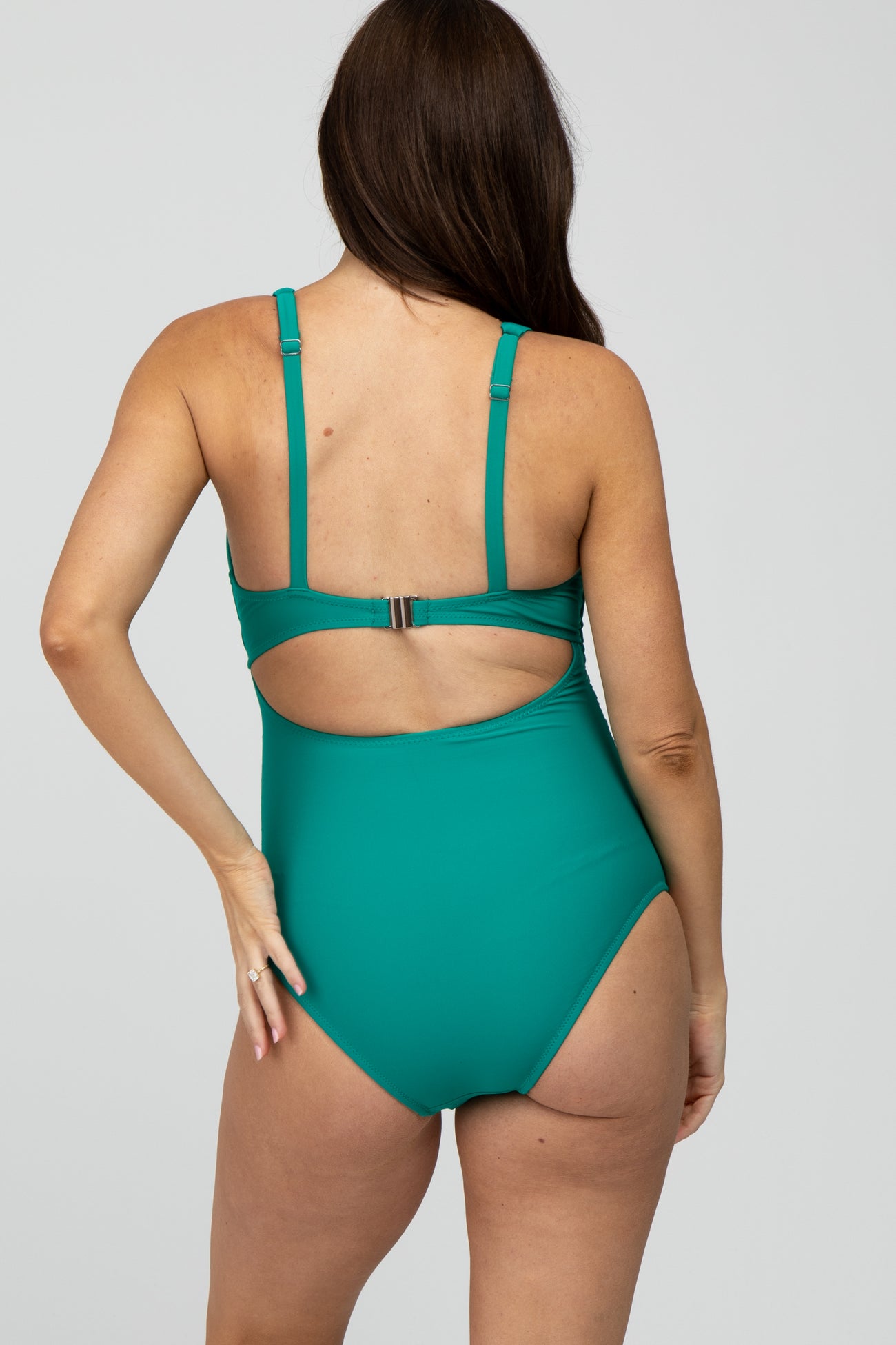 woman wearing a teal maternity swimsuit with a stylish cut-out back and adjustable straps