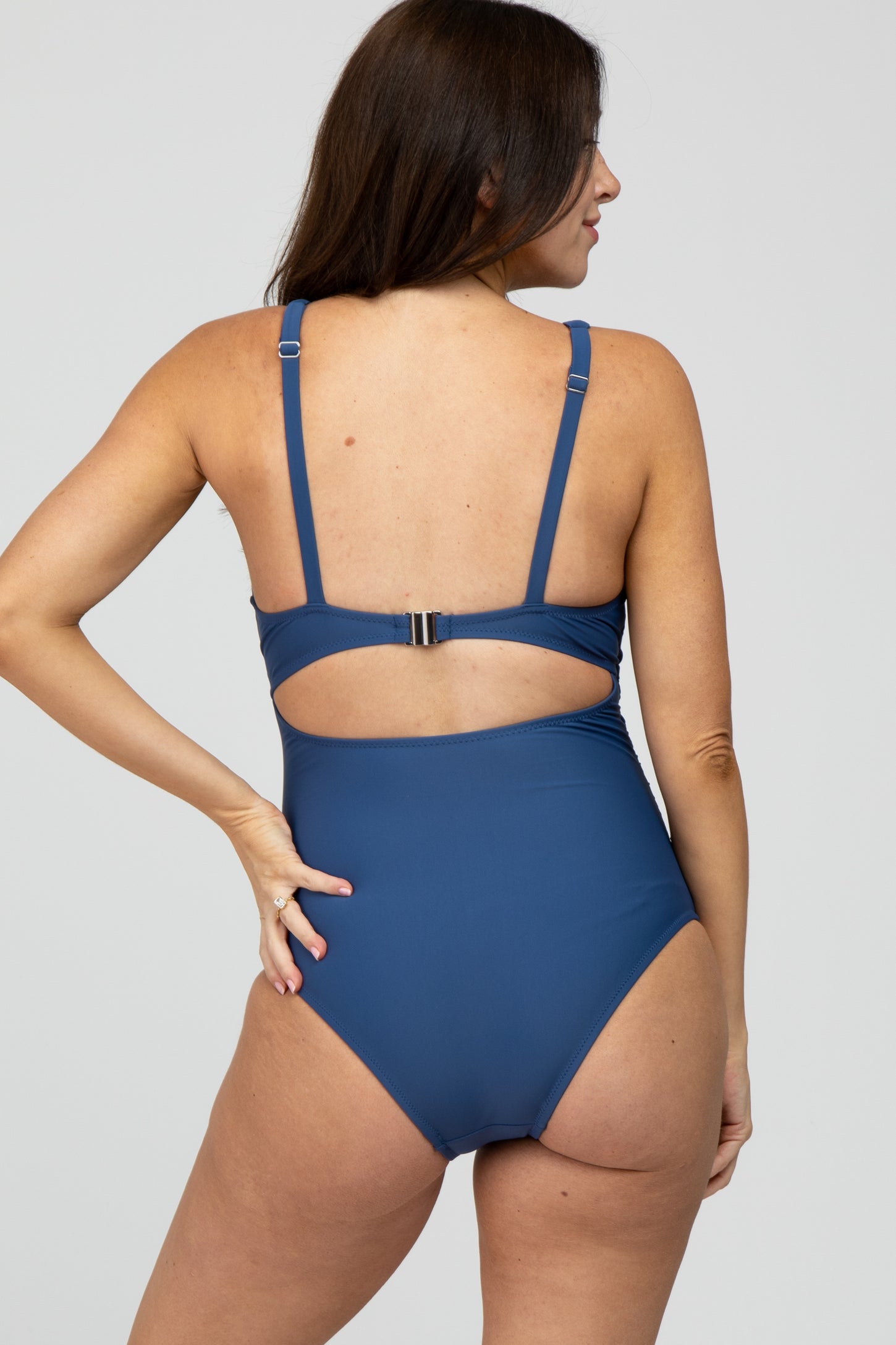 woman wearing a navy blue maternity one-piece swimsuit with a cutout back design