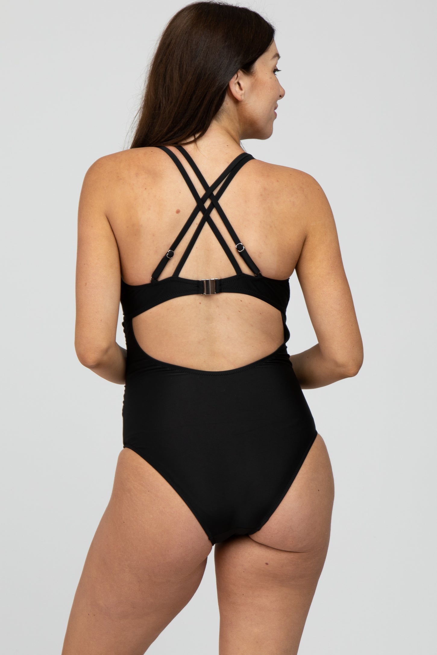woman wearing a black maternity one-piece swimsuit with crisscross straps and a low back