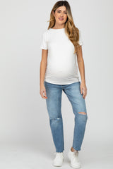 woman wearing a white short sleeve maternity top and distressed light blue maternity jeans, showing a visible baby bump