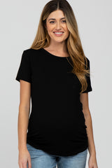 woman wearing a black short sleeve maternity top and showing her baby bump