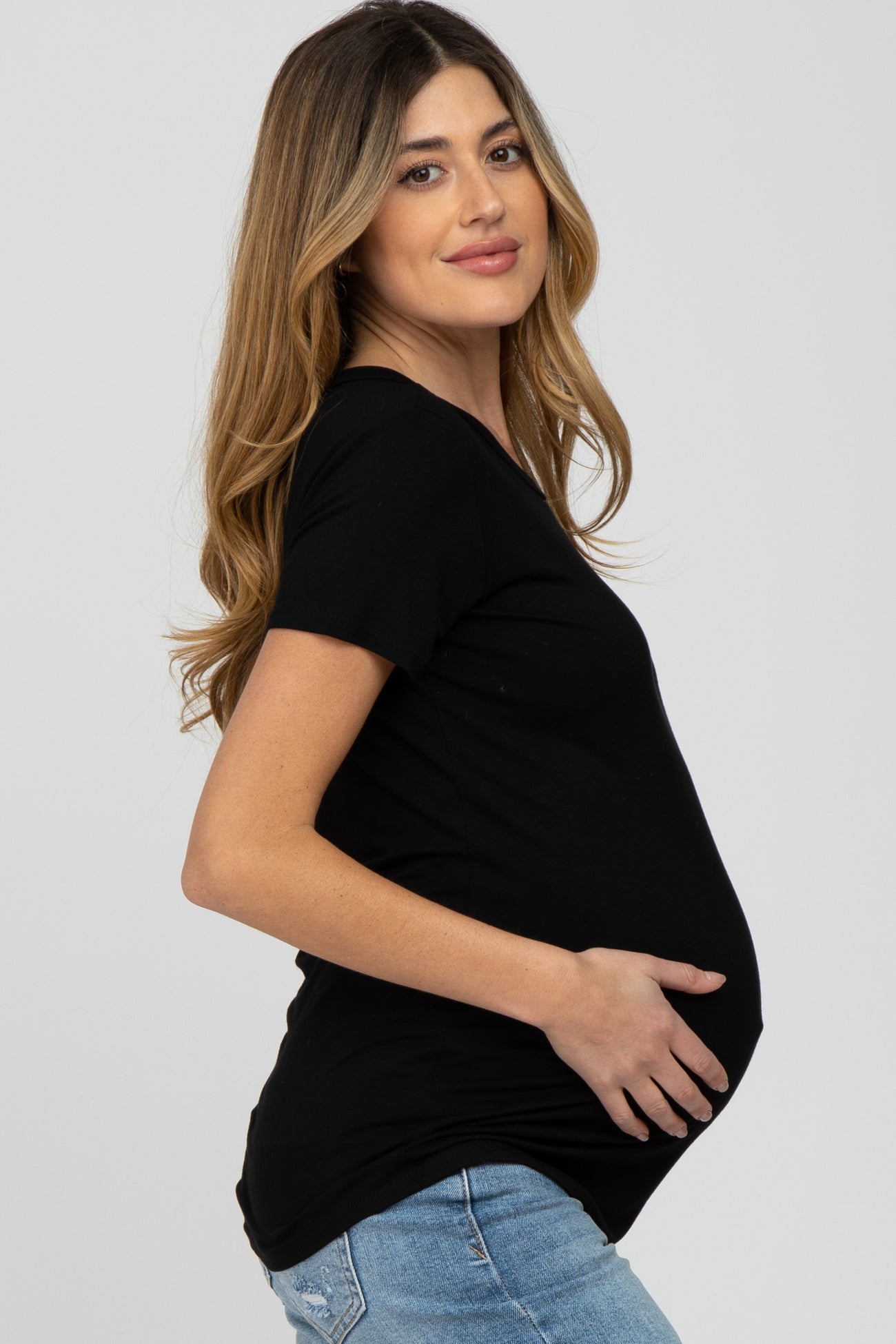 woman wearing a black short sleeve maternity top and showing her baby bump