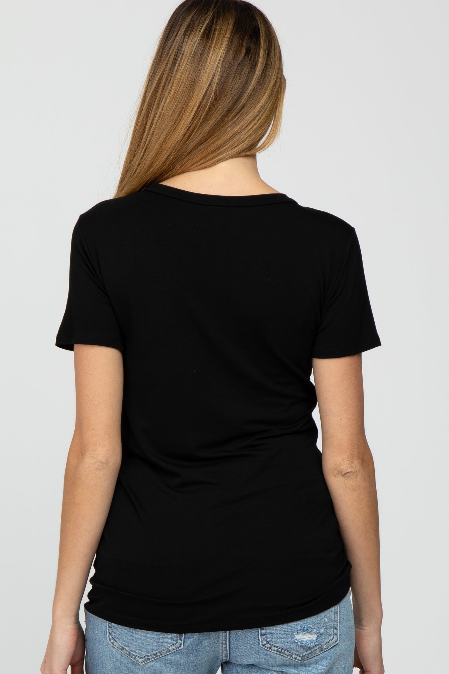 woman wearing a black short sleeve maternity top, viewed from the back, paired with light blue jeans