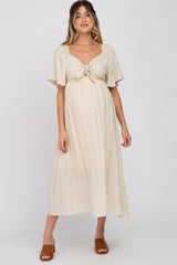 woman wearing a cream maternity dress with short flutter sleeves and a knotted front detail, showing her baby bump