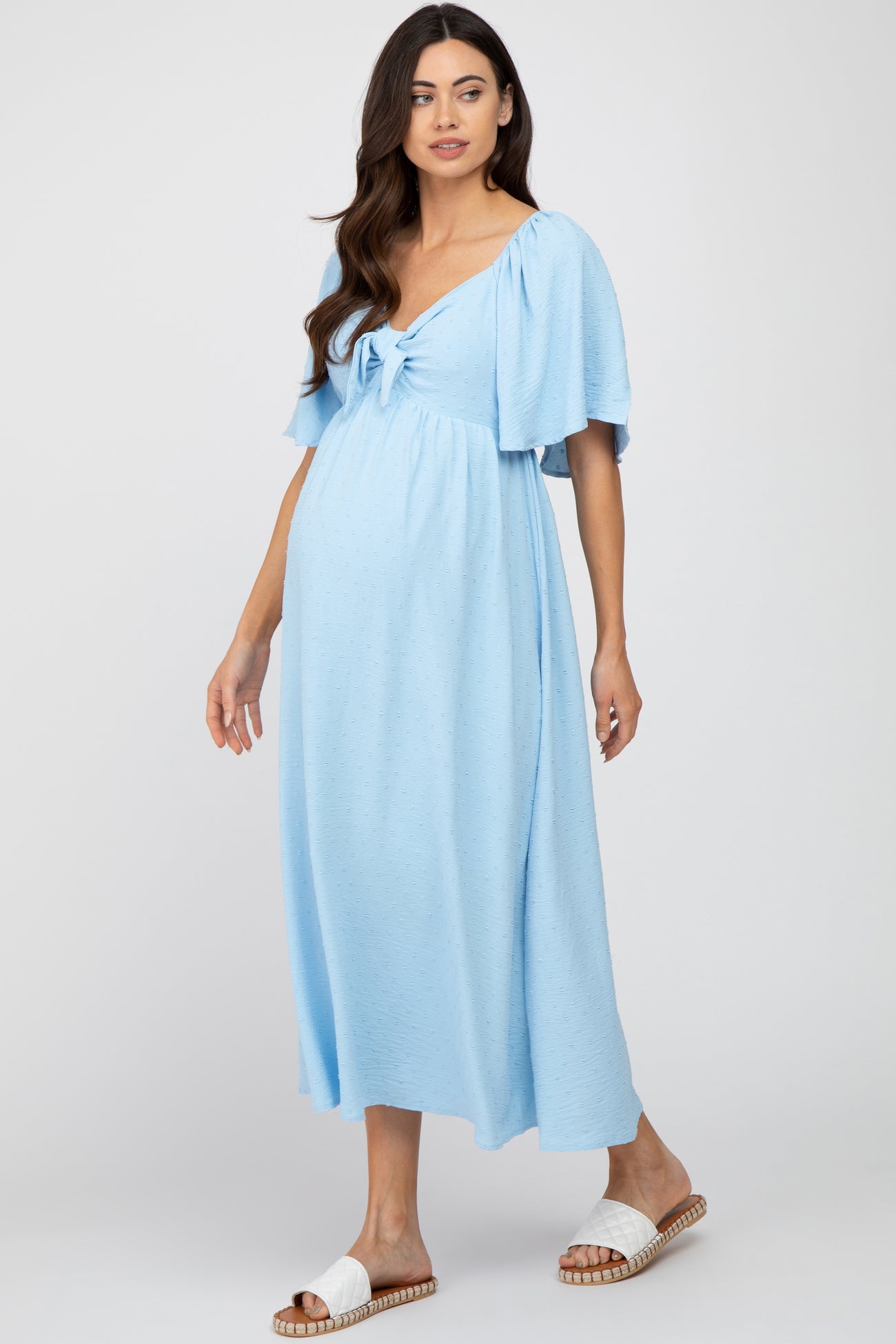 woman wearing a light blue maternity maxi dress with short puff sleeves and a tie front, showing her baby bump