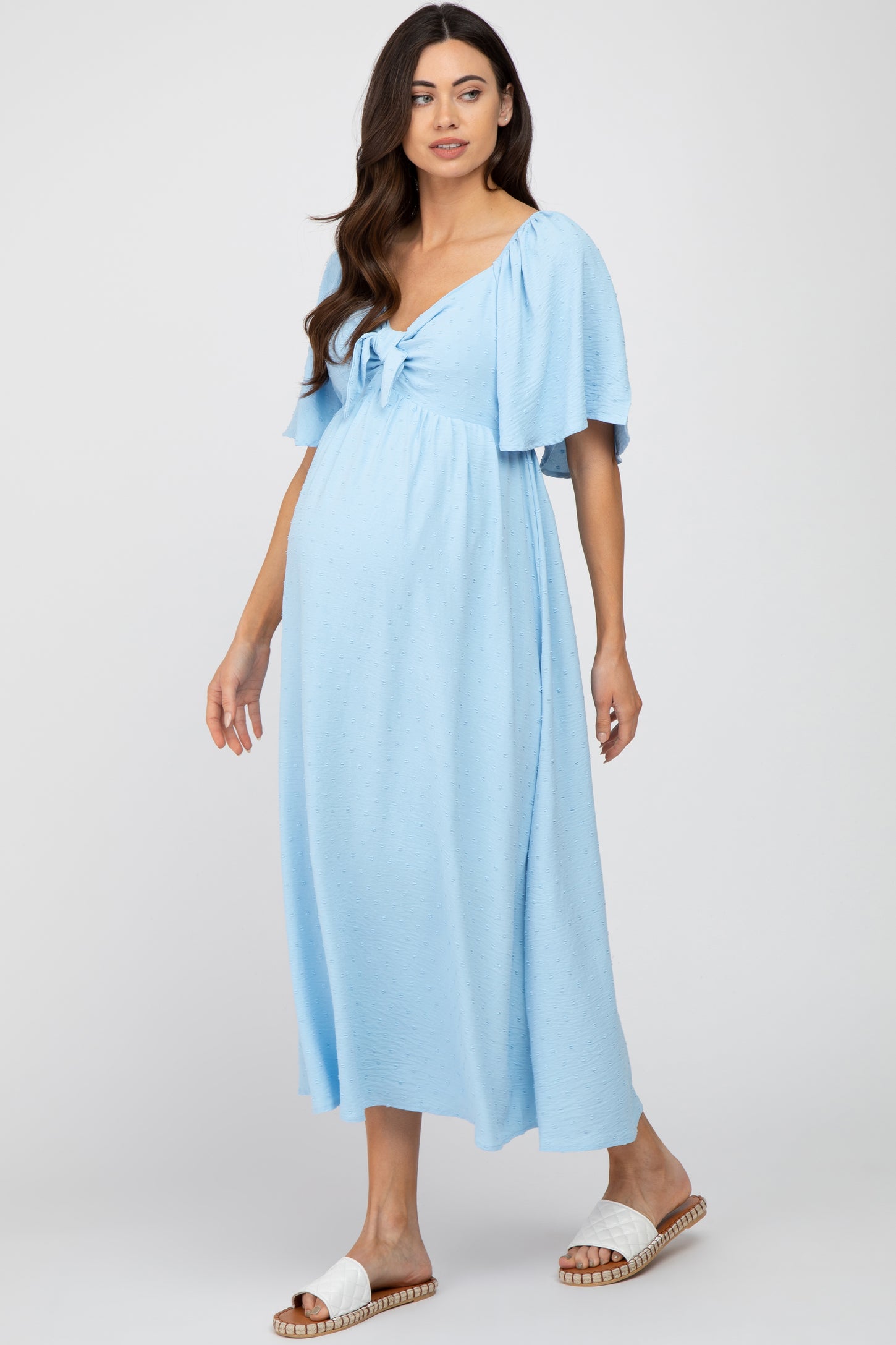 woman wearing a light blue maternity maxi dress with short puff sleeves and a tie front, showing her baby bump
