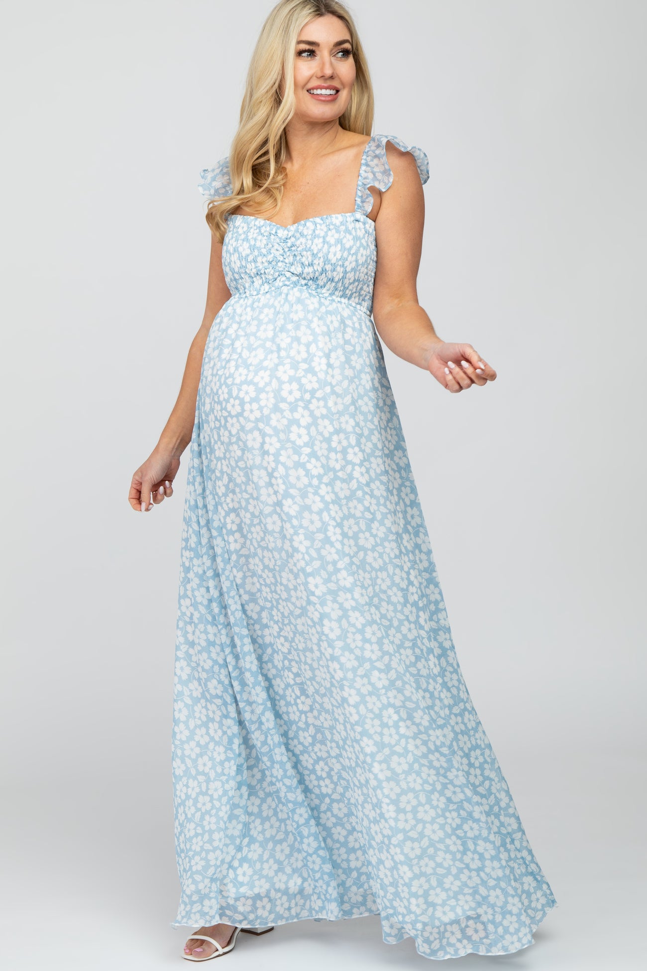 woman wearing a light blue floral maternity maxi dress with ruffled straps and a visible baby bump
