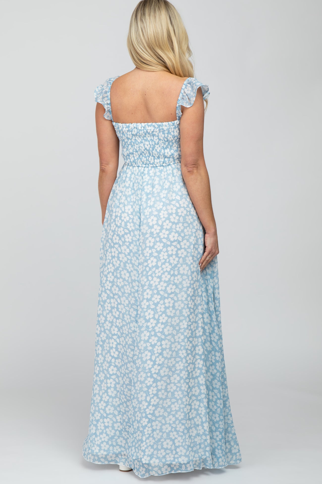 woman wearing a light blue maternity maxi dress with floral print and ruffle sleeves, shown from the back